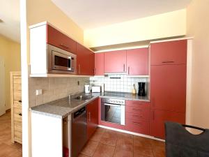 eine Küche mit roten Schränken und einer Spüle in der Unterkunft Südwind Apartment Nr 05 - FeWo Usedom, strandnah, Schwimmbad, Sauna, Parkplatz, WLAN, und Balkon in Zempin