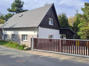 a white house with a black roof and a fence at Chalupa na lužické stezce in Svor