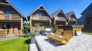 a group of chairs sitting on a patio in front of a house at Seaside domki in Mielno