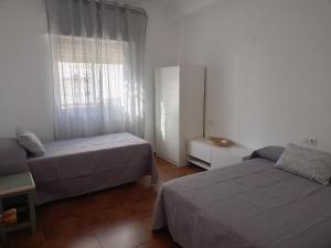 a small bedroom with two beds and a window at Casa Feria in Algodonales