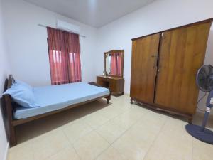 a bedroom with a bed and a cabinet and a fan at Garden Cottage Homestay BB in Wattala