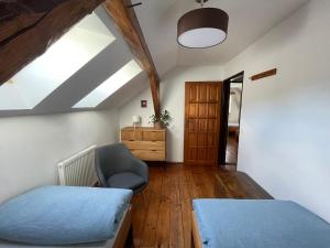 a attic room with two beds and a chair at Tyllichova Chata in Hejnice