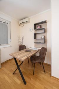 a dining room with a wooden table and two chairs at Apartment Orchid 021 in Novi Sad