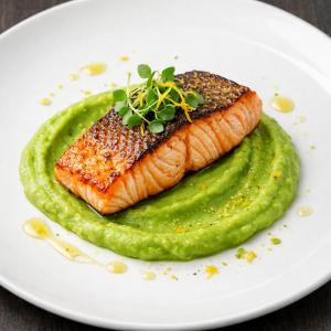 a white plate with a piece of salmon and a green sauce at Penzion Eška s Pivovarem MJ in Jince