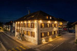 a white building with lights on it on a street at Hôtel de la Couronne in Les Bois