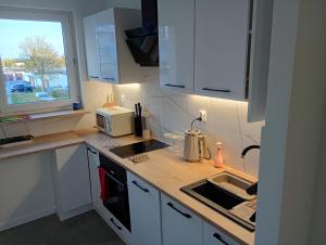 a kitchen with white cabinets and a sink and a window at Apartament Niebieskie in Zamość