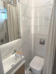 a white bathroom with a toilet and a sink at Skiron House in Skala Kallirachis
