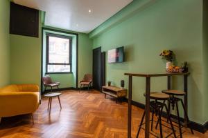 a living room with green walls and a table and chairs at Edinburgh Centre - Holyrood Apartment in Edinburgh