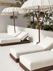 a row of white beds with umbrellas on display at Terracotta House in Porto Santo