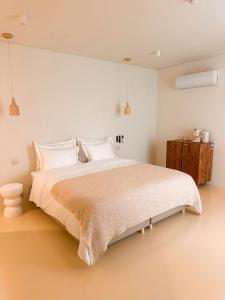 a bedroom with a large bed with white walls at Terracotta House in Porto Santo