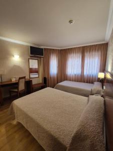 a hotel room with two beds and a desk at Hotel HHB Pontevedra Confort in Pontevedra