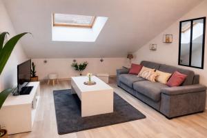 a living room with a couch and a tv at Charmant Loft climatisé 50 m de la gare in Chalon-sur-Saône