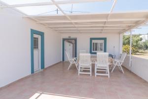 a patio with white chairs and a table on it at Xenia's House in Kefalos