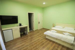 a bedroom with a bed and a desk with a television at Prime Heaven in Chiatʼura