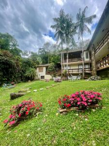 a green yard with pink flowers and a building at Flat Salto Dagua Penedo in Penedo +9 photos