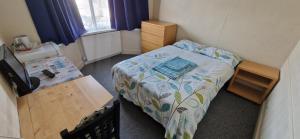 a small bedroom with a bed and a desk at Chezzas Homestay in Poole