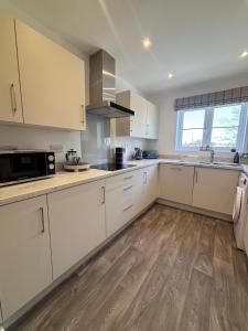 Eine Küche mit weißen Schränken und Holzboden in der Unterkunft Oakfield View in Credenhill