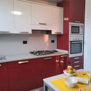 a kitchen with red cabinets and a bowl of fruit on a table at A Rimirar il Lago Mountain Lake Iseo Hospitality in Bossico