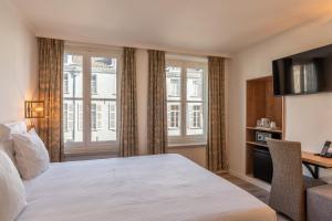 a hotel room with a bed and a desk and windows at Hotel Bryghia in Bruges