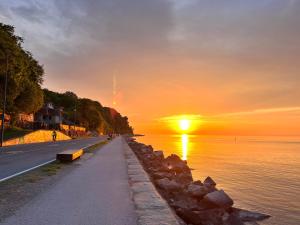 a road next to a body of water with a sunset at DeLux Apartment Koper - NEW in Koper