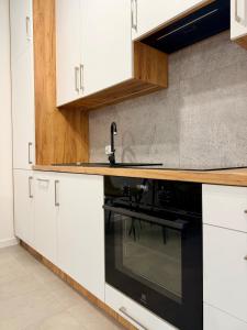 a kitchen with white cabinets and a black oven at Apartament KJ Tomice in Tomice