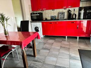 a kitchen with red cabinets and a red table at La croisée des chemins in Vions