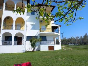 a white building with balconies and a green field at Thalassoudis-House 2 in Agios Nikolaos