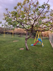 a playground with a tree and a swing at Thalassoudis-House 2 in Agios Nikolaos