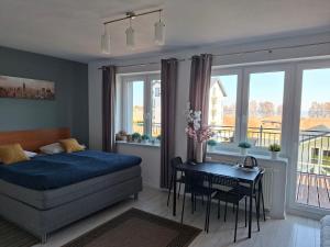 a bedroom with a bed and a table and windows at Azalia 32 Mielno l in Mielno