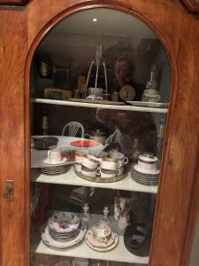a cabinet with plates and cups and dishes in it at Villa Conte Private Urban Hideaway in Wels
