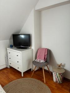 a living room with a tv and a chair at Harcsa Vendégház Tiszafüred in Tiszafüred