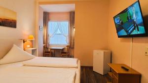 a hotel room with two beds and a flat screen tv at Hotel Münchner Löwenbräu in Cuxhaven