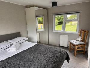 a bedroom with a bed and a chair and two windows at Toad Hall Suite in Chelmsford