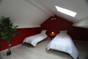 two beds in a room with a red wall at Appart Hotel cholet centre in Cholet