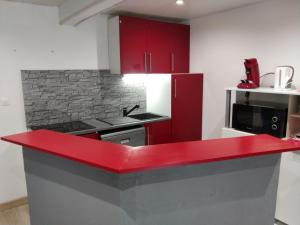 a red counter top in a kitchen with red cabinets at Appart Hotel cholet centre in Cholet