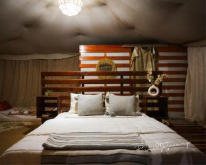 a bedroom with a large bed with a wooden headboard at Rimal tata camp in Migourdâne