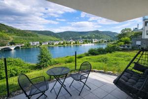 a patio with a table and chairs and a river at MV Römerlodge mit einmaligem Moselpanoramablick in Treis-Karden