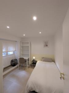 a white bedroom with a bed and a desk at PisoCentro in Santander