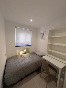 a bedroom with a bed and a desk and a window at PisoCentro in Santander
