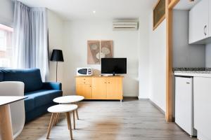 a living room with a blue couch and a tv at Apartamentos Laforja in Barcelona