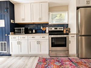 a kitchen with white cabinets and stainless steel appliances at NEW Beach Cozy Bungalow 2B Mins-beach&downtown in Clearwater