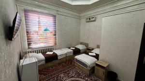 a room with four beds and a window at Deshon Qala Guest House in Khiva