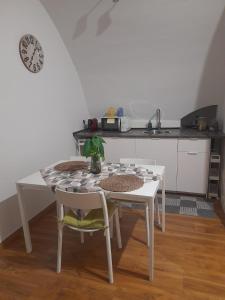 a white table and chairs in a kitchen with a table and a clock at La casetta nel cuore di Sciò in Gioia del Colle