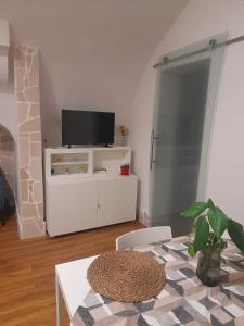 a living room with a tv on a white entertainment center at La casetta nel cuore di Sciò in Gioia del Colle +5 photos