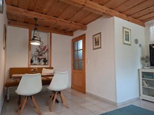 a dining room with a table and two white chairs at Ferienhaus Weingarten Eisenberg in Vaskeresztes