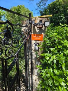 an iron gate with a sign on it next to plants at La chambre d'hôtes de l'olivier Gîte A Coeur Vaillant in Vailhan
