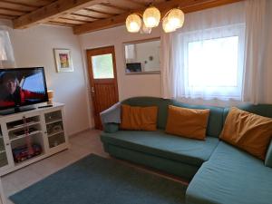 a living room with a blue couch and a tv at Ferienhaus Weingarten Eisenberg in Vaskeresztes