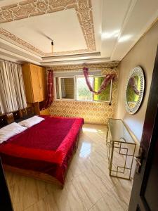 a bedroom with a red bed and a glass table at Nador cornich calme in Nador