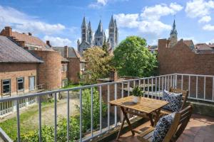 a balcony with a table and chairs and a view of cathedral at Appartements Entiers - Centre de Tournai in Tournai