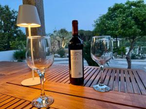 a bottle of wine and two wine glasses on a table at Villa Peru in Tanaunella
